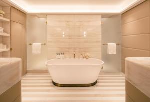 a white bath tub sitting in a bathroom next to a sink at Four Seasons Hotel London at Park Lane in London