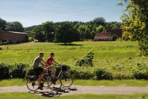 dos personas montando bicicletas en un camino de tierra en un campo en Hotel Pension Marie-Luise, Hotel garni, en Bad Bevensen