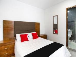 - une chambre avec un grand lit et des oreillers rouges dans l'établissement Capital O San Jose, San Luis Potosi, à San Luis Potosí