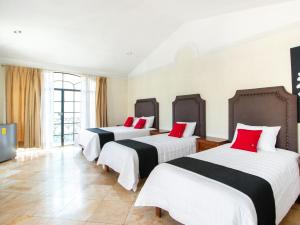 Cette chambre comprend 3 lits avec des oreillers rouges. dans l'établissement Capital O San Jose, San Luis Potosi, à San Luis Potosí