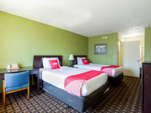Habitación con 2 camas, paredes verdes y escritorio. en OYO Hotel Pensacola I-10 & Hwy 29, en Pensacola