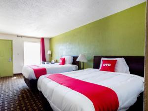 two beds in a hotel room with red and white sheets at OYO Hotel Pensacola I-10 & Hwy 29 in Pensacola