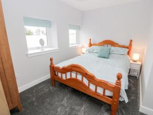 1 dormitorio con cama de madera y ventana en Meadowbank, en Girvan