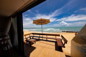 a balcony with a bench and an umbrella on the beach at SuRFCoRe House in Baía Formosa