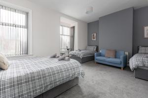 um quarto com 2 camas e uma cadeira azul em Raikes Parade Victorian Holiday Home - Blackpool Resort Collection em Blackpool