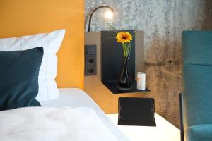 a bedroom with a bed with a vase with a flower in it at LOGINN Hotel Leipzig in Leipzig