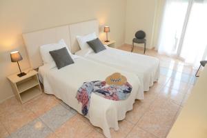 two white beds in a room with two lamps at Rallye Hotel in L'Escala