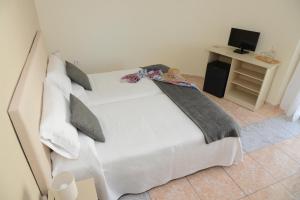a bedroom with a white bed with pillows and a desk at Rallye Hotel in L'Escala