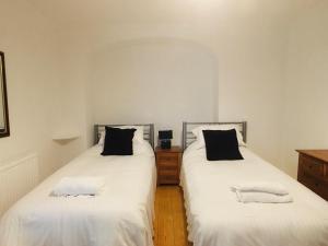 a bedroom with two beds with white sheets and black pillows at MyCityHaven South Parade Mansions in Bristol