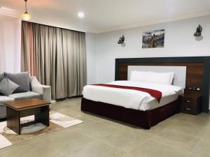 a bedroom with a bed and a chair and a couch at MY HOTEL Nizwa Residence Hotel Apartments نزوى ريزيدنس للشقق الفندقيه in Nizwa +35 photos