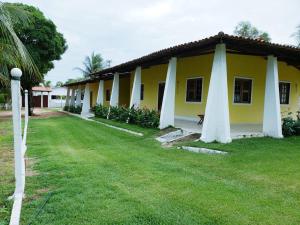 a yellow and white building with a grass yard at Casa de 4 quartos á 6Km da praia de Lagoinha-ce in Camboa