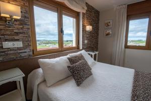 um quarto com uma cama com duas almofadas e duas janelas em Hotel el Pinar em Villapedre