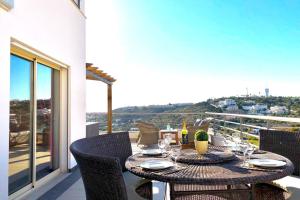 einen Tisch auf einem Balkon mit Stadtblick in der Unterkunft Albufeira l AMAZING terrasse with jacuzzi Encosta da Orada in Albufeira