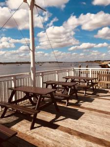 three picnic tables sitting on a dock near the water at Ye Olde White Harte Hotel in Burnham-on-Crouch