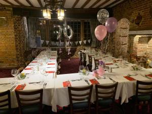 a long table with white tables and pink balloons at Ye Olde White Harte Hotel in Burnham-on-Crouch