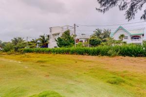 a house on a grassy hill with houses in the background at Palmetto#1 @ Island Cabanas in Caye Caulker