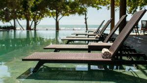 a row of empty chairs sitting in the water at Kûara Hotel in Arraial d'Ajuda