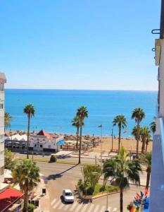 a view of a beach with palm trees and the ocean at Victoria luxury beachfront apartment in Benalmadena Costa in Benalmádena
