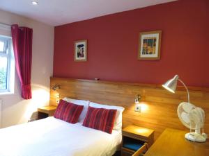 ein Schlafzimmer mit einem Bett und einer roten Wand in der Unterkunft Cherry Lodge in Hook