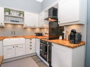 une cuisine avec des placards blancs et un comptoir dans l'établissement 1 Craiganrioch, à Campbeltown