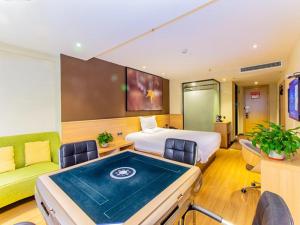 貴陽市にあるIU Hotel Guiyang Future Ark Poly New City Guiyu Hot Spring Storeのベッドと緑のソファが備わるホテルルームです。