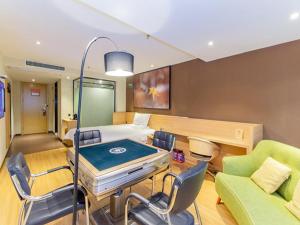 a room with a bed and a table and chairs at IU Hotel Guiyang Future Ark Poly New City Guiyu Hot Spring Store in Guiyang