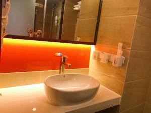 a white sink in a bathroom with a mirror at 7Days Premium Guiyang North Station in Guiyang