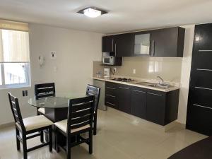 a kitchen with a table and chairs and a kitchen with black cabinets at Grupo Kings Suites - Monte Chimborazo 567 in Mexico City