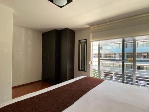 a bedroom with a bed and a large window at Grupo Kings Suites - Monte Chimborazo 567 in Mexico City