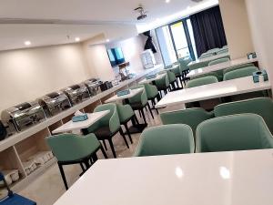 ein Vorlesungsraum mit grünen Stühlen, Tischen und Schreibtischen in der Unterkunft Xana Hotel Guiyang International Convention and Exhibition Center Financial City Store in Guiyang
