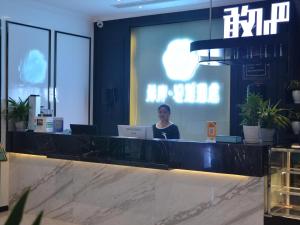 a woman sitting at a counter in a lobby at Xana Hotel Guiyang Huaxi Park in Guiyang