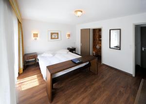 a bedroom with a bed and a desk in it at Hotel Römerhof in Leukerbad