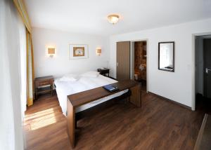 ein Schlafzimmer mit einem Bett und einem Schreibtisch. in der Unterkunft Hotel Römerhof in Leukerbad