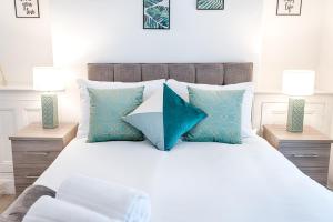 a bed with blue and white pillows and two lamps at Working in Swansea - Try us out in Swansea
