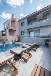 un patio con bancos y una piscina frente a una casa en Emmeleia mare, en Agia Pelagia