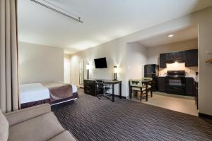 Habitación de hotel con cama, escritorio y cocina en Residency Suites, en Cotulla