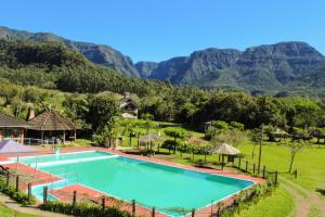 a swimming pool with mountains in the background at Pousada & Camping Nativos dos Canyons in Praia Grande