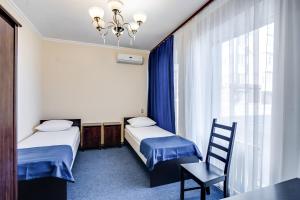 a room with two beds and a chair and a window at Hotel Teatralny in Rostov on Don
