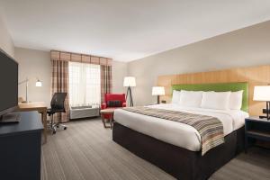 シャンバーグにあるCountry Inn & Suites by Radisson, Schaumburg, ILの大きなベッドとデスクが備わるホテルルームです。