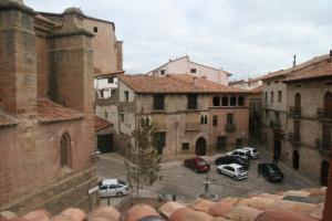 un gruppo di auto parcheggiate in un parcheggio tra edifici di Apartamentos La Iglesia a Mora de Rubielos