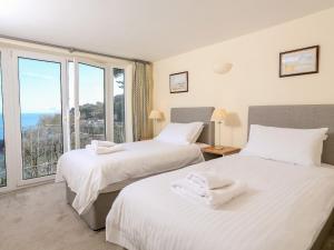 two beds in a bedroom with a view of the ocean at Courtenay Villa in Salcombe
