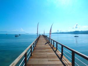 a wooden pier with two sailboats on the water at Kokomo Resort Gili Gede in Gili Gede