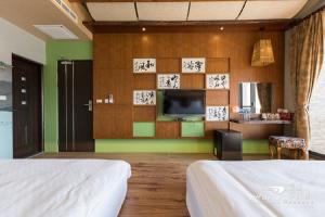 a hotel room with two beds and a television at 花蓮好客靚屋民宿Hakka Beauty House in Ji'an