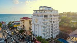 ein hohes weißes Gebäude mit einer Uhr am Meer in der Unterkunft Aristocrat Residence & Hotel in Sihanoukville