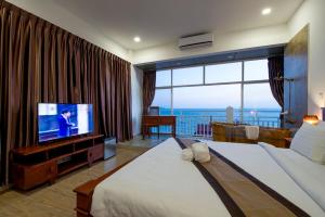 ein Hotelzimmer mit einem großen Bett und einem Fernseher in der Unterkunft Aristocrat Residence & Hotel in Sihanoukville
