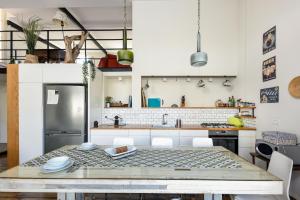 a kitchen with a table and a refrigerator at TLV Loft Paradise with Balcony, Roof Top & Mamad by Sea N' Rent in Tel Aviv