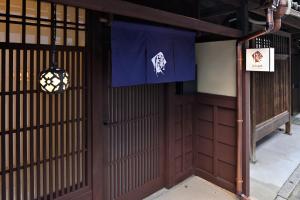 Una entrada a un edificio con una pancarta azul. en Kyo no Ondokoro MARUTAMACHI #7, en Kioto