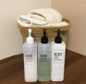 three bottles of hair products next to a basket of towels at Coco Fukuoka Chiyo in Fukuoka