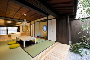 a living room with a table and yellow cushions at Kyo no Ondokoro MARUTAMACHI #7 in Kyoto