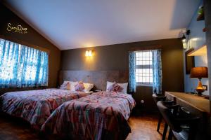 a bedroom with two beds and a desk and two windows at snow drop villa in Kodaikānāl